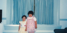 Two young girls posing in front of a window